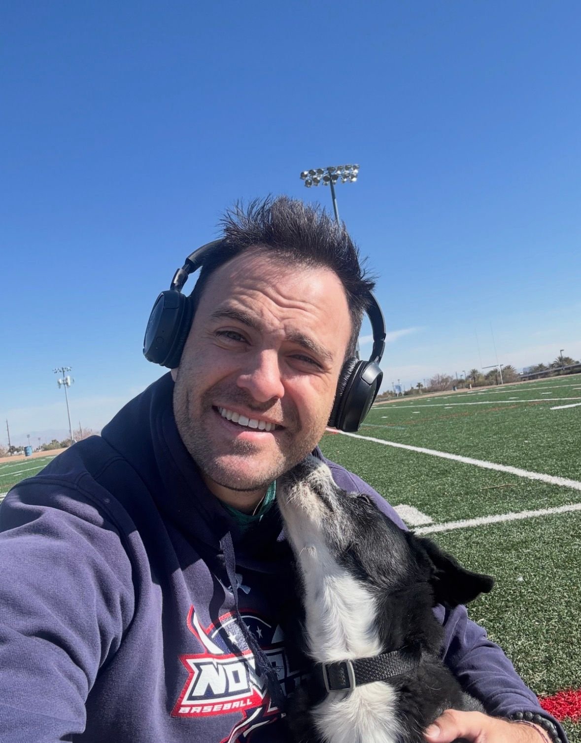 Jeff smiling outdoors on a sunny field with a dog